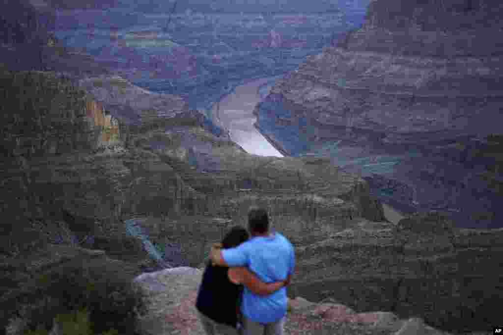 FILE - Alyssa Chubbuck, left, and Dan Bennett embrace while watching the sunset at Guano Point overlooking the Colorado River on the Hualapai reservation, Aug. 15, 2022.