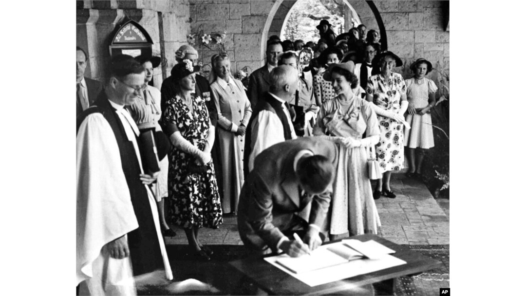 FILE - Britain's Princess Elizabeth talks with the Bishop of Mombasa while her husband, Prince Philip, the Duke of Edinburgh signs the visitors book at All Saints Cathedral, in Nairobi, on Feb. 2, 1952.