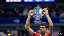 Petenis asal Spanyol, Carlos Alcaraz, mengangkat trofi kemenangan setelah mengalahkan petenis Norwegia casper Ruud dalam laga puncak AS Terbuka. Partai final turnamen tersebut digelar di New York, pada 11 September 2022. (Foto: AP/Matt Rourke)