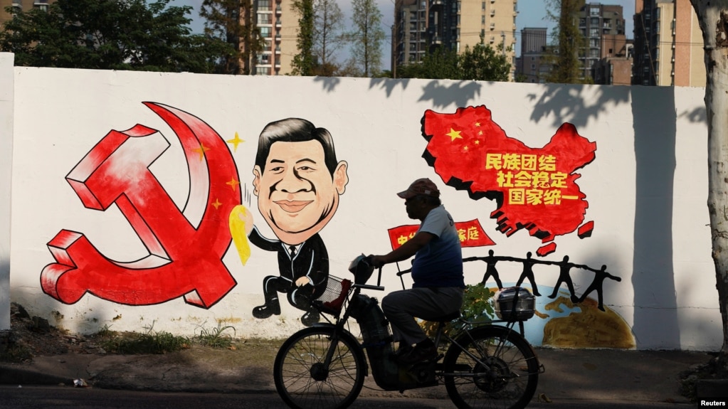 资料照：一名男子骑车路过北京街头一面印有习近平画像的宣传画。（2018年9月28日）(photo:VOA)