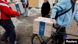 People carry boxes as they receive humanitarian help organized by the municipality and the World Food Program, in Kramatorsk, Donetsk region, Sept. 6, 2022.