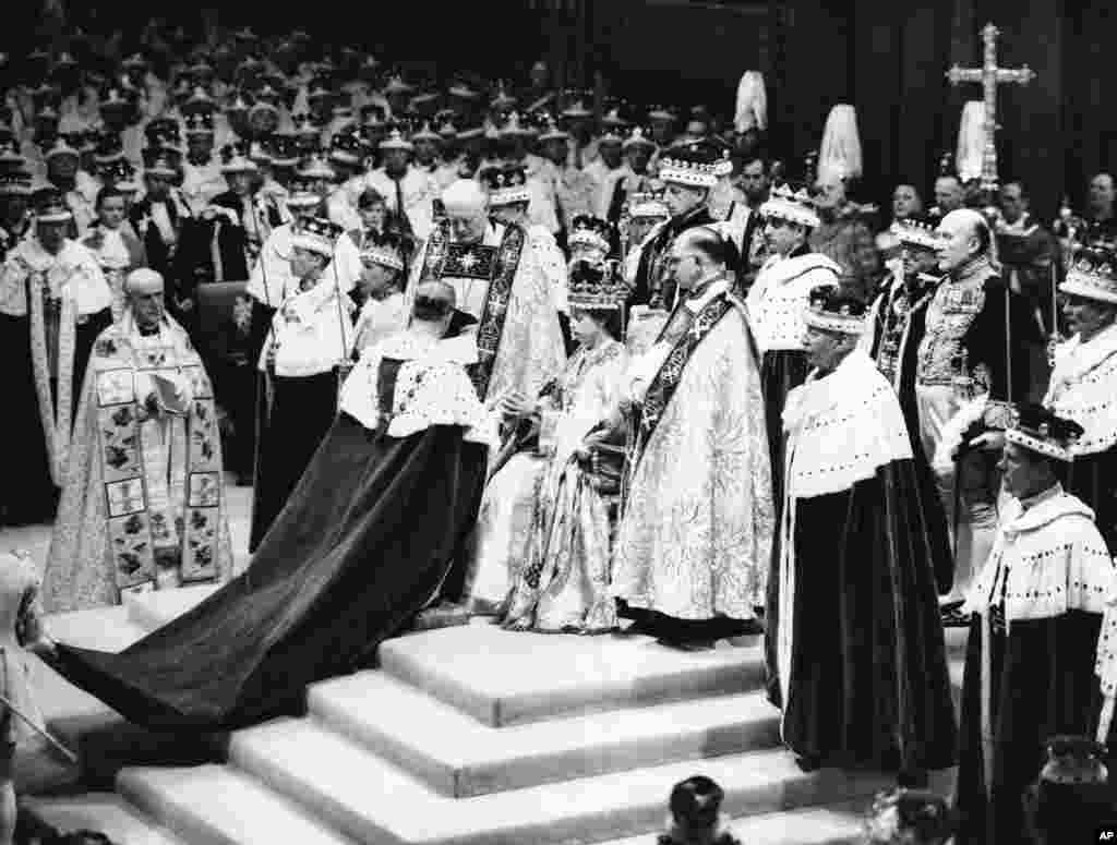 Surrounded by clerics and ladies-in-waiting, Queen Elizabeth II sits in the Chair of Estate in Westminster Abbey, London, June 2, 1953, before being crowned.