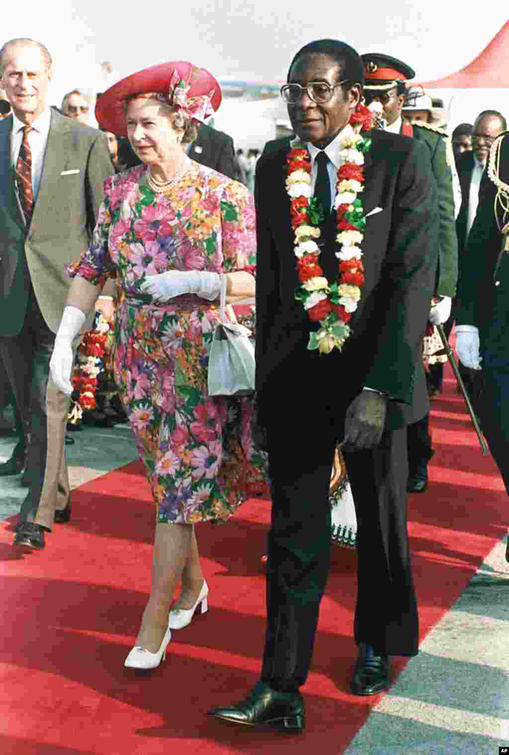 In this file photo taken Oct. 10, 1991 Britain&#39;s Queen Elizabeth II is escorted by Zimbabwean President Robert Mugabe, right, after the Queen&#39;s arrival at Harare airport on a second visit to the country.&nbsp;