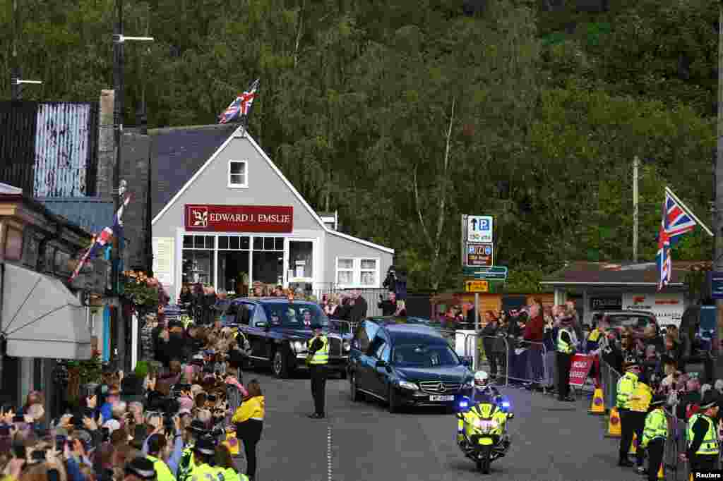 People line the street as the hearse carrying the coffin of Britain&#39;s Queen Elizabeth passes through the village of Ballater, near Balmoral, Sept. 11, 2022.