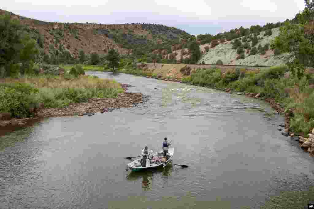 FILE - Fisherman on a boat float on the Colorado River, June 27, 2021, near Burns, Colo. 