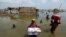 Women carry belongings from their flooded home after monsoon rains, in the Qambar Shahdadkot district of Sindh province, Pakistan, Sept. 6, 2022. Millions have lost their homes in flooding this year that many experts have blamed on climate change.