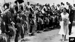 FILE - Queen Elizabeth II and the Prince Philip inspect a group of Torres Strait Islanders who had just put on a display of tribal dancing for the royal couple at the welcoming ceremony in the Queensland town of Cairns, Australia on March 13, 1954.