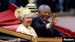 FILE - South African President Nelson Mandela is accompanied by Britain's Queen Elizabeth II in a carriage ride to a Buckingham Palace lunch on the first day of his state visit to Britain July 9, 1996.
