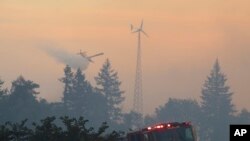 FILE- Firefighters use aircraft to battle a wildfire south of Salem, Ore., Sept. 9, 2022 as Oregon utilities cut power to customers in a bid to lessen the risk of wildfires.