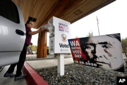 FILE - Lummi Nation tribal member Karen Scott drops her completed ballot into a ballot drop box on Oct. 19, 2020, on the Lummi Reservation, near Bellingham, Washington.