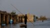 A man rows his boat as he passes through flooded market, following rains and floods during the monsoon season in Bajara village, at the banks of Manchar lake, in Sehwan, Pakistan, Sept. 6, 2022. 