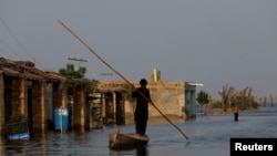 A man rows his boat as he passes through flooded market, following rains and floods during the monsoon season in Bajara village, at the banks of Manchar lake, in Sehwan, Pakistan, Sept. 6, 2022. 