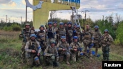 Ukrainian service members pose in the recently liberated settlement of Vasylenkove, in the Kharkiv region, Ukraine, in this photo released Sept. 10, 2022, by the press service of the Territorial Defense of the Ukrainian Armed Forces.