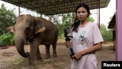 FILE - Elephant owner Siriporn Sapmak, 23, poses while holding her gear used for social media live-streaming outside her house, at Ban Ta Klang village in Surin, Thailand April 6, 2022.