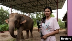 FILE - Elephant owner Siriporn Sapmak, 23, poses while holding her gear used for social media live-streaming outside her house, at Ban Ta Klang village in Surin, Thailand April 6, 2022.