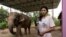 FILE - Elephant owner Siriporn Sapmak, 23, poses while holding her gear used for social media live-streaming outside her house, at Ban Ta Klang village in Surin, Thailand April 6, 2022.
