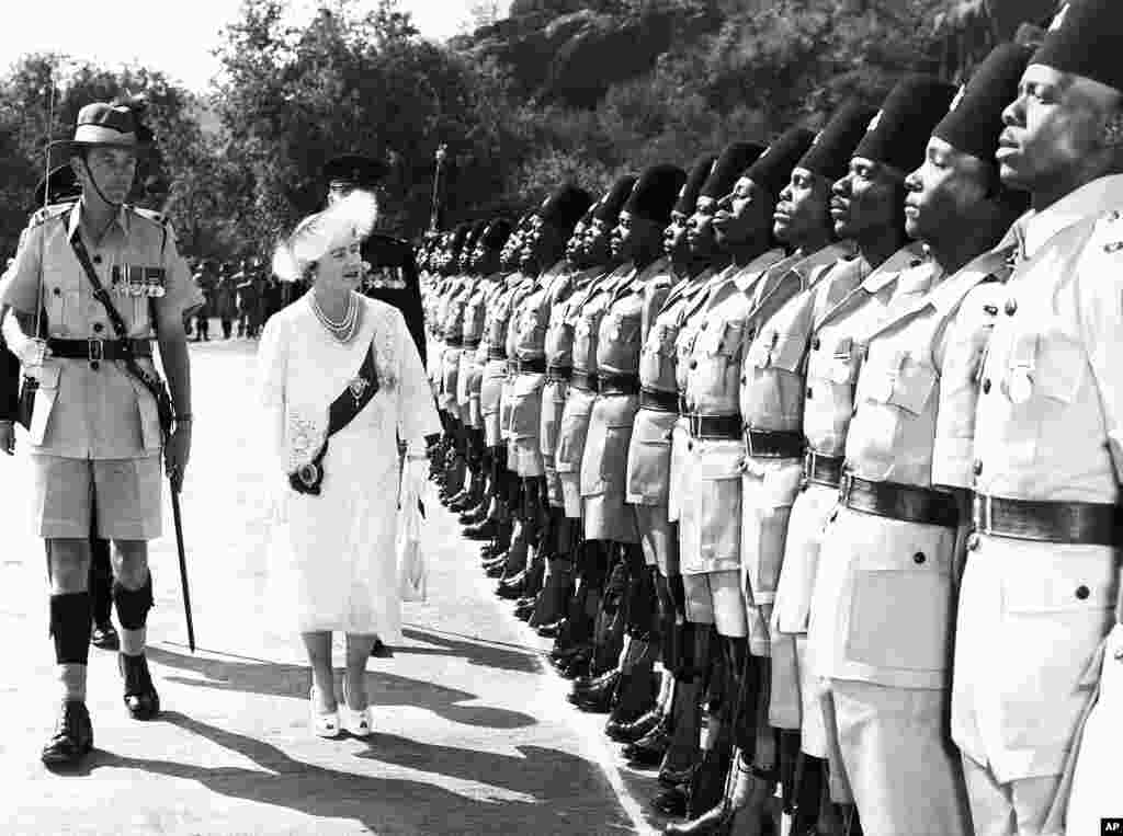 Queen Elizabeth, the Queen Mother accompanied by the guard commander Major R. Aikenhead, inspects a guard of honor of the Second Battalion the Kings African rifles at the great Indaba in the Matotos Hills, near then Bullawayo, Rhodesia on July 8, 1957.