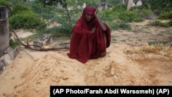 FILE: Fatuma Abdi Aliyow sits by the graves of her two sons who died of malnutrition-related diseases last week, oyutside Mogadishu, Somalia Saturday, Sept. 3, 2022. Millions of people in the Horn of Africa region are going hungry because of drought, and thousands have died.