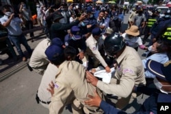 Local security personnel try to grab a banner from supporters of the Cambodia National Rescue Party in front of the the Phnom Penh Municipal Court in Phnom Penh on June 14, 2022. (Heng Sinith/AP)