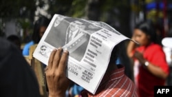 Un hombre se protege del sol con un periódico que tiene en portada una foto del presidente Nicolás Maduro, en la plaza de Bolívar en Caracas el 6 de febrero de 2019.