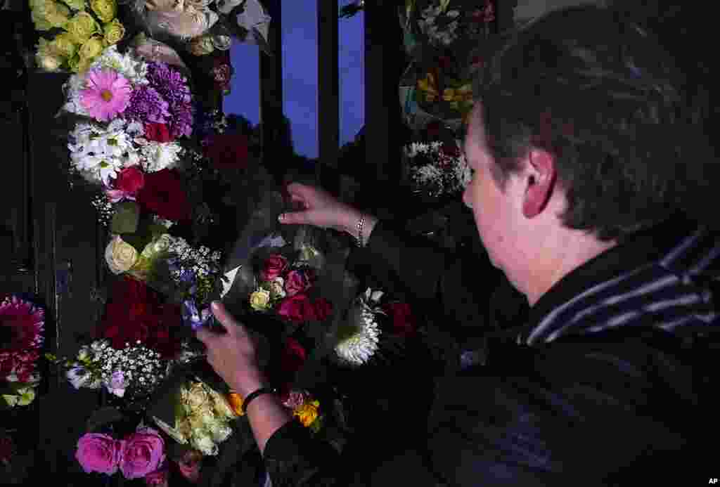 A woman leaves a floral arrangement, after the announcement of the death of Queen Elizabeth II, in front of Buckingham Palace in London, Sept. 8, 2022. 