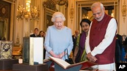 FILE - Britain's Queen Elizabeth II and Indian Prime Minister Narendra Modi view items of interest, put on display from the Royal Collection, at Buckingham Palace in London, during his visit to the United Kingdom, Nov. 13, 2015. 