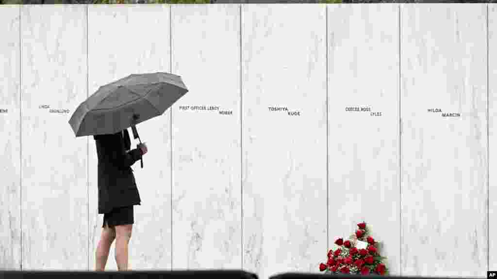 یک بازدیدکننده در شنکسویل، ایالت پنسیلوانیا، مقابل دیواری که اسامی جان&zwnj;باختکان پرواز شماره ۹۳ روی آن نوشته شده ایستاده است (یکشنبه ۱۱ سپتامبر ۲۰۲۲)