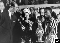 FILE - In this Nov. 10, 1968 file photo, Britain's Queen Elizabeth II with Prince Philip present a cup to soccer player Pele, right, at a stadium in Rio de Janeiro, Brazil, during a state tour of South America. Buckingham Palace officials say Prince Philip, the husband of Queen Elizabeth II, has died, it was announced on Friday, April 9, 2021. He was 99. Philip spent a month in hospital earlier this year before being released on March 16 to return to Windsor Castle. Philip, also known as the Duke of Edinburgh, married Elizabeth in 1947 and was the longest-serving consort in British history. (AP Photo/File)