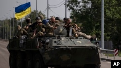 FILE - Ukrainian servicemen ride atop of an armored vehicle on a road in Donetsk region, eastern Ukraine.