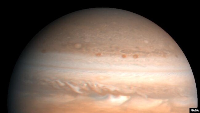 This processed color image of Jupiter was produced in 1990 by the U.S. Geological Survey from a Voyager image captured in 1979. The colors have been enhanced to bring out detail. Zones of light-colored, ascending clouds alternate with bands of dark, desce