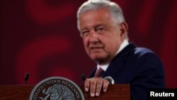 FILE - Mexico's President Andres Manuel Lopez Obrador rests his hand on a lectern during a news conference at the National Palace in Mexico City, Mexico, June 20, 2022.