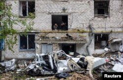 Orang-orang merokok sambil membersihkan puing-puing bangunan tempat tinggal yang hancur akibat serangan di Mykolaiv, Ukraina, 11 September 2022. (Foto: Reuters)