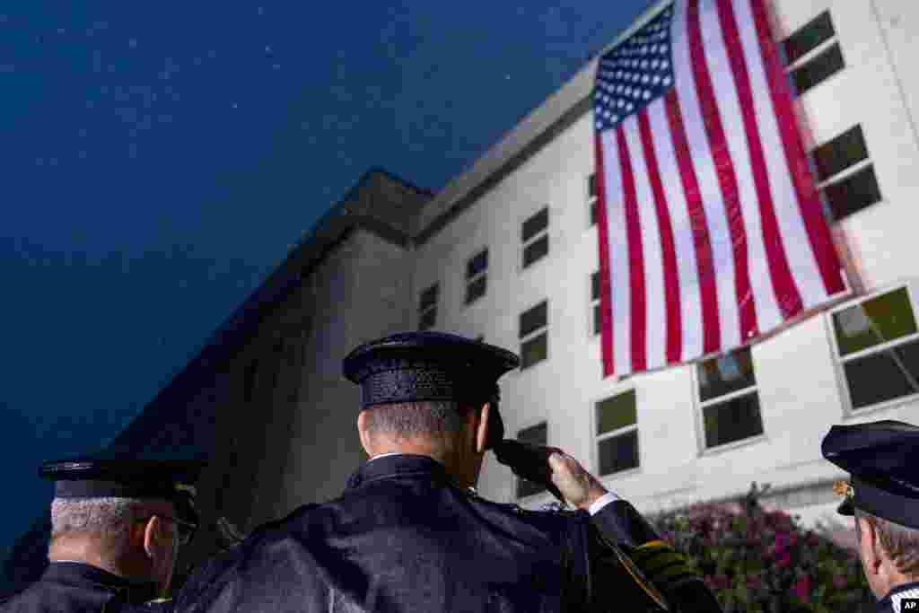 First responders salute as a U.S. flag is unfurled at the Pentagon in Washington, Sept. 11, 2022, at sunrise on the morning of the 21st anniversary of the 9/11 terrorist attacks.