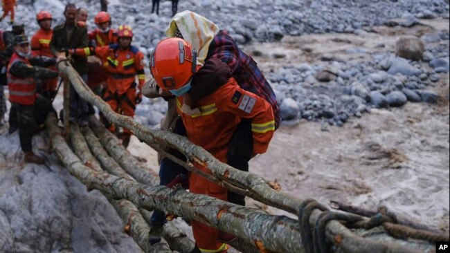 In this photo released by Xinhua News Agency, rescuers carry a villager across a river following an earthquake in Moxi Town of Luding County, southwest China's Sichuan Province on Monday, Sept. 5, 2022. (Cheng Xueli/Xinhua via AP)