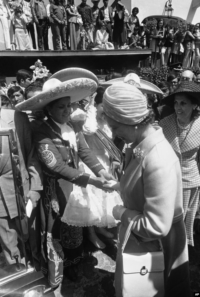 Una joven con traje de mariachi saluda a la reina Isabel II durante fiesta mexicana en honor a la soberana británica durante su visita al país azteca el 25 de febrero de 1975. La reina visitó durante seis días el territorio mexicano y fue recibida con homenajes.