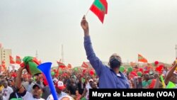 FILE: A man raises a small party flag in the crowd. Cazenga, Luanda. Taken 8.22.2022