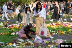 People visit floral tributes placed in Green Park near Buckingham Palace, following the death of Britain's Queen Elizabeth, in London, Sept. 11, 2022.