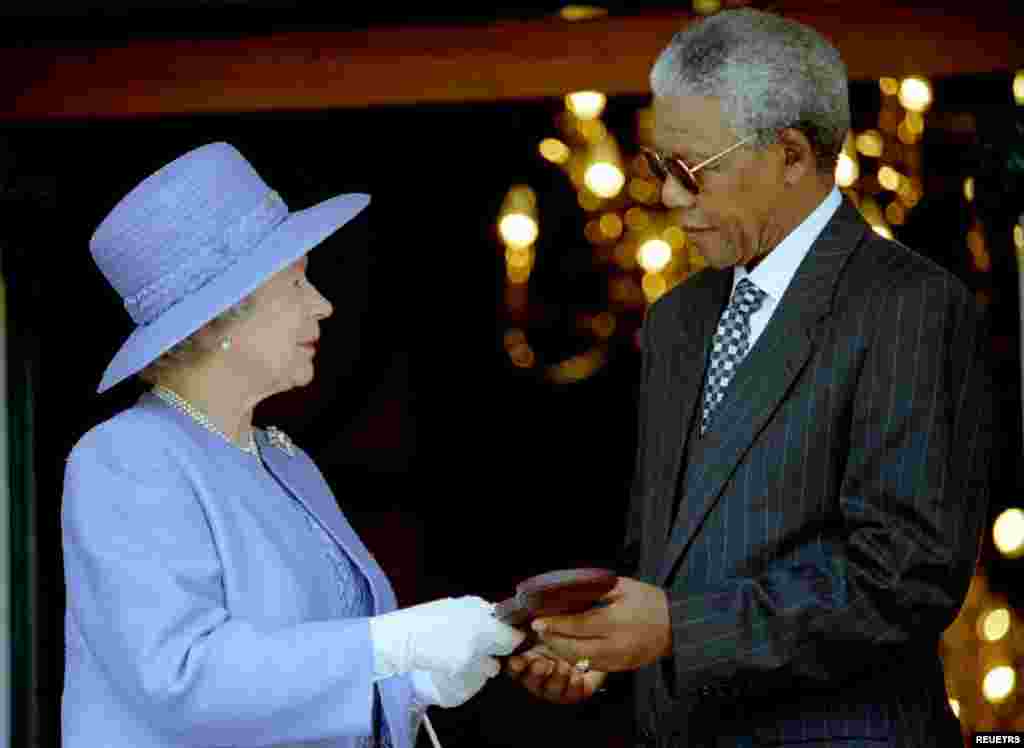 Britain&#39;s Queen Elizabeth II presents the Order of Merit medal to President Nelson Mandela at the start of a brief meeting at Mandela&#39;s office, March 20, 1995. The Queen is in South Africa, her first to the country since 1947