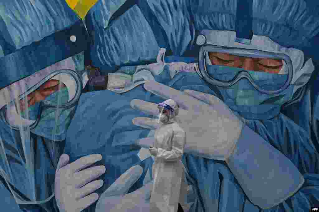 A medical personnel wearing a protective suit waits at the COVID-19 drive-thru test center outside the Ajwa Private Clinic in Shah Alam on the outskirts of Kuala Lumpur, as Malaysia&#39;s king declared a state of emergency to fight a coronavirus surge.