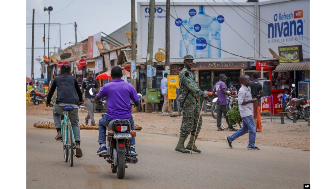 FILE - A military officer observes traffic at a checkpoint set up to stop motorcycles carrying passengers, in an attempt to limit the spread of Ebola, in Mubende, Uganda, Nov. 1, 2022.
