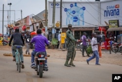 FILE - A military officer observes traffic at a checkpoint set up to stop motorcycles carrying passengers, in an attempt to limit the spread of Ebola, in Mubende, Uganda, Nov. 1, 2022.