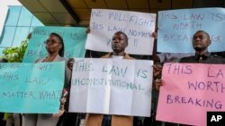 FILE - Digital activists hold placards as they demonstrate after submitting a legal petition against controversial new legislation criminalizing some internet activity, at the Constitutional Court in Kampala, Uganda, Oct. 17, 2022.