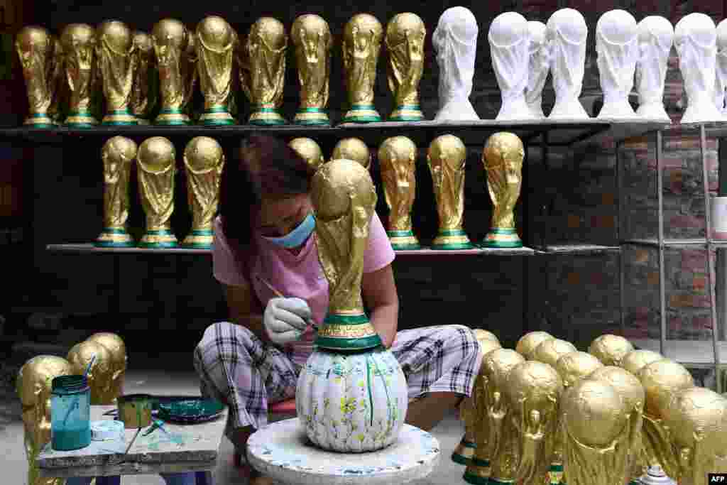 A worker paints a plaster model of the FIFA World Cup trophy at a workshop in Hanoi, Vietnam, ahead of the Qatar 2022 World Cup football tournament.