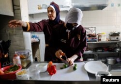 Koki Palestina Amena Al-Hayek mengamati staf yang bekerja di Sabaia VIP, restoran khusus perempuan yang baru dibuka, di Kota Gaza, 6 September 2022. (REUTERS/Mohammed Salem)