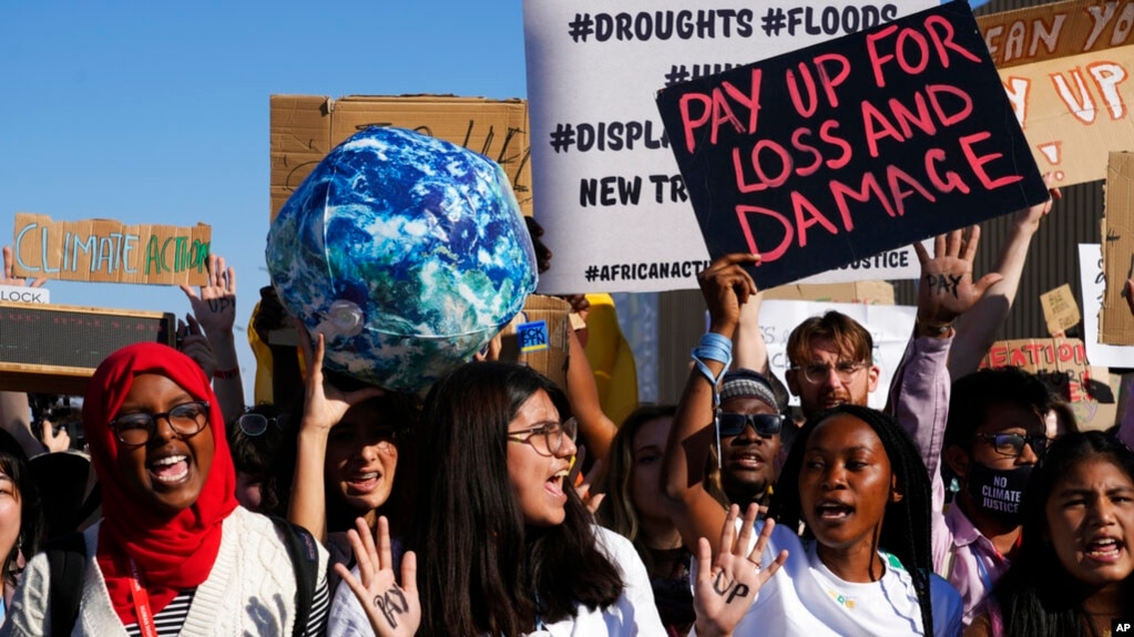 在埃及举行的COP27联合国气候大会会场外，活动人士高举写着“支付损失与损害”的标语牌。(2022年11月18日)