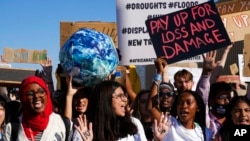在埃及举行的COP27联合国气候大会会场外，活动人士高举写着“支付损失与损害”的标语牌。(2022年11月18日)