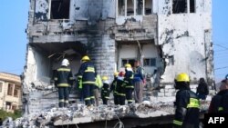 People gather as firefighters search for victims and survivors under the rubble of a building which collapsed after gas tank exploded, in the northern Iraqi city of Suleimaniyah, on Nov. 18, 2022.
