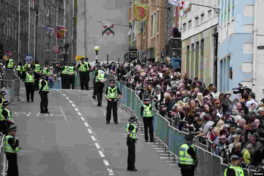 People wait at The Royal Mile for the arrival of the hearse carrying the coffin of Britain's Queen Elizabeth, in Edinburgh, Scotland, Sept. 11, 2022.