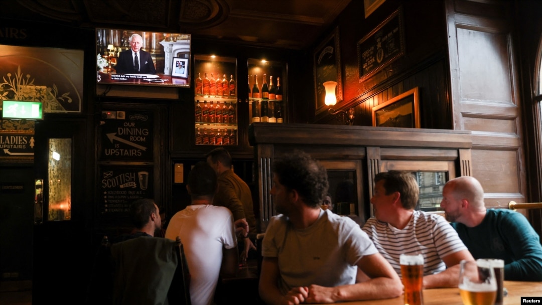 La gente ve al rey Carlos de Inglaterra dirigirse a la nación en un discurso televisado, tras el fallecimiento de la reina Isabel II, en la taberna Deacon Brodie, en Edimburgo, Escocia, el 9 de septiembre de 2022.