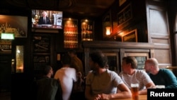 La gente ve al rey Carlos de Inglaterra dirigirse a la nación en un discurso televisado, tras el fallecimiento de la reina Isabel II, en la taberna Deacon Brodie, en Edimburgo, Escocia, el 9 de septiembre de 2022.